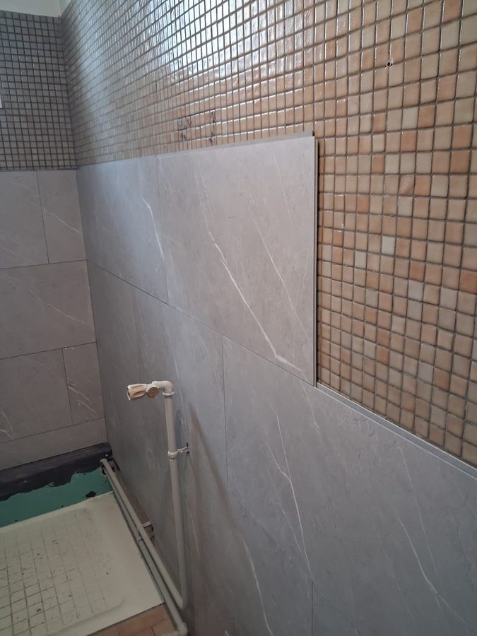 Chantier de rénovation salle de bain — pose carrelage grand format sur mosaïque existante